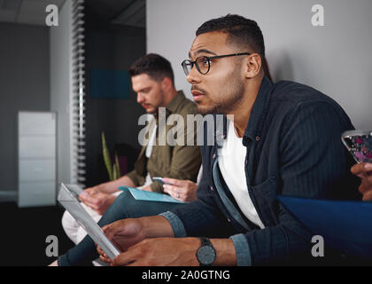 Portrait d'un african american man reprendre dans sa main en attente d'entrevue d'emploi avec d'autres candidats dans l'entreprise - du vrai foi Banque D'Images