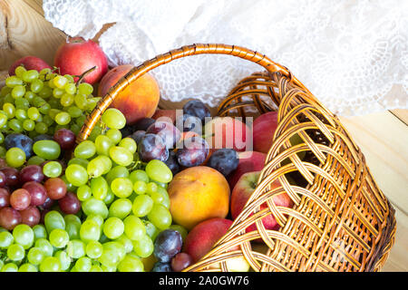 Nouvelle récolte de fond. Tas de fruits frais de panier en osier sur table en bois recouvert de tissu. Banque D'Images