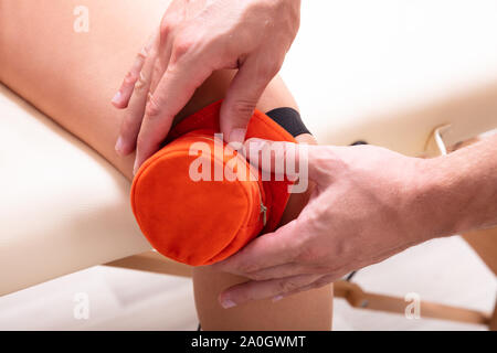 Close-up d'un thérapeute de sexe masculin la moxibustion donnant sur les traitements en clinique du genou du patient Banque D'Images