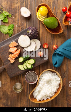 Ingrédients pour préparation bol avec poke saumon, avocat, de légumes et de graines de chia sur fond de bois Vue de dessus Banque D'Images
