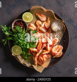 Crevettes crues dans une casserole avec les ingrédients pour la cuisson sur un fond sombre vue de dessus Banque D'Images