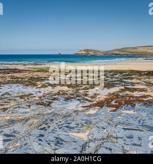 Une belle journée ensoleillée à Constantine Bay, Cornwall, Angleterre montrant le rocher gris, algues, sable, mer de l'Atlantique et de pointe en milieu rural. Banque D'Images