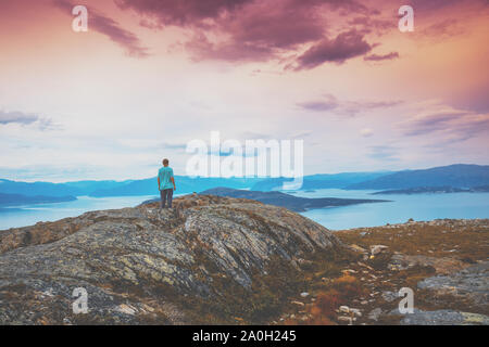 Vue panoramique sur le fjord. Le Crépuscule du temps avec le ciel rose. Le jeune homme debout sur la falaise de roche et regardant la mer. Belle Montagne l Banque D'Images