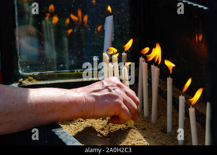 Woman's hand met la bougie enflammée dans l'église. La Religion. Banque D'Images