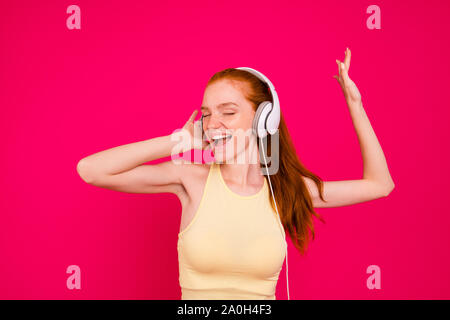 Portrait of cute nice belle extase adorable positif attrayant fille rousse dans tanktop, écouter de la musique disco, les yeux fermés, chantant, isoler Banque D'Images