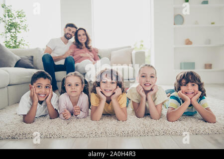 Belle photo de cinq enfants multiethnique jeter près de canapé confort floue sur le doux tapis à la lumière lumineux salon télévision Banque D'Images