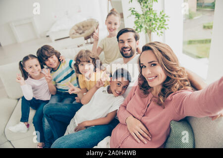 Maman fait photo photo selfies avec grande famille pour son blog, s'asseoir sur blanc confort, canapé confortable ou dans la table de l'intérieur moderne et lumineux appartement Banque D'Images