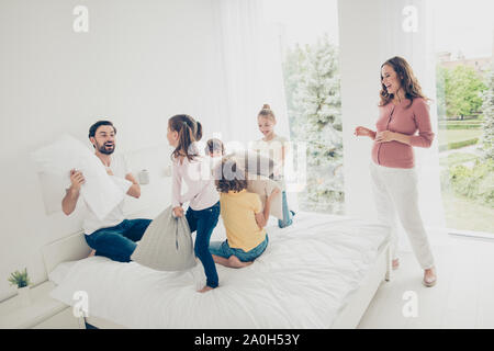 Grande belle belle belle famille adoptive gaies, six personnes, femmes enceintes, maman et papa barbu preteen quatre enfants jouant avec des oreillers, lumière blanche Banque D'Images