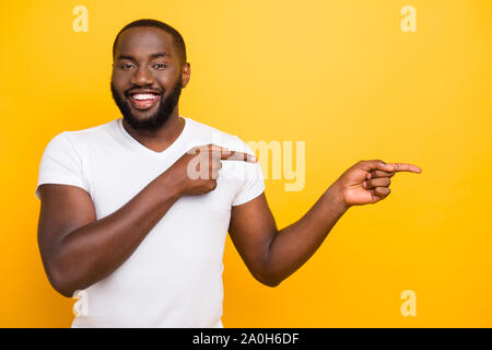 Attrayant beau mulâtre manly cheerful heureux satisfait l'homme, pointant avec deux doigts de côté, isolé sur fond jaune vif lumineux Banque D'Images