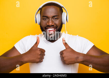 Portrait of handsome man mulâtre choqué dans les casques, montrant le double thumbs-up, isolé sur fond jaune vif lumineux Banque D'Images