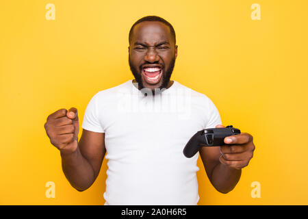 Portrait de choqué funny funky crazy heureux heureux homme mulato, Jouer, gagner le jeu en ligne, bouche ouverte, plus isolés jaune vif lumineux retour Banque D'Images