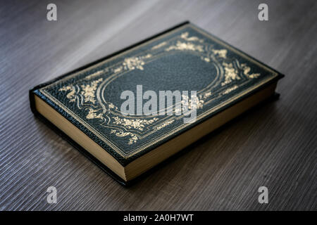 Livre Ancien avec couvercle vert avec des décorations d'or reposant sur la table en bois Banque D'Images