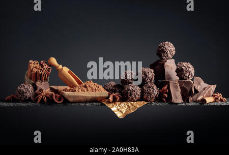 Truffes au chocolat avec des morceaux de chocolat et d'épices. Le chocolat, les bâtons de cannelle et anis sur fond sombre. Copier l'espace. Banque D'Images