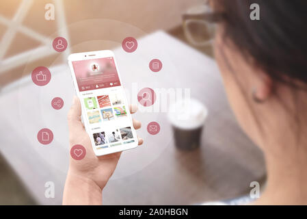 L'utilisation du réseau social fille app sur téléphone intelligent. Concept de marketing de réseau social et de promotion. Banque D'Images