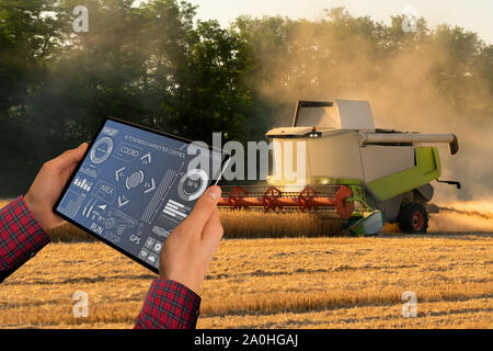 Fermier utilise une tablette numérique pour contrôler l'ensileuse autonome. Concept d'agriculture intelligente. Banque D'Images