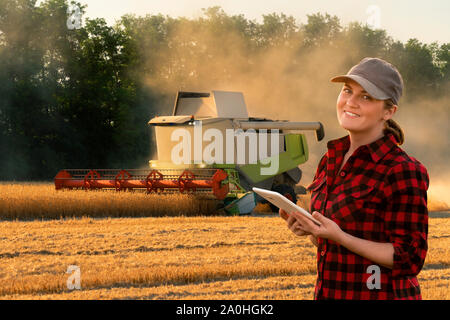 Fermier utilise une tablette numérique pour contrôler l'ensileuse autonome. Concept d'agriculture intelligente. Banque D'Images