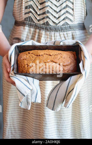 Young woman's hands holding un pain fraîchement cuit au four de pain de potiron maison cuit dans un moule à pain d'époque. Selective focus sur du pain sucré avec b floue Banque D'Images