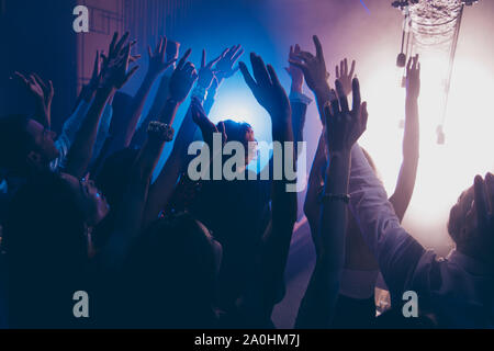 Cheering live show performance concept. Foule de gens à l'ombre pendant un concert de danse partie club avec néons soulevées les mains en arrière-plan Banque D'Images