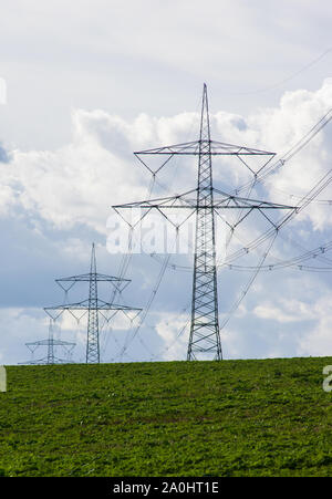 Pylônes sur champ vert en face de ciel nuageux Banque D'Images