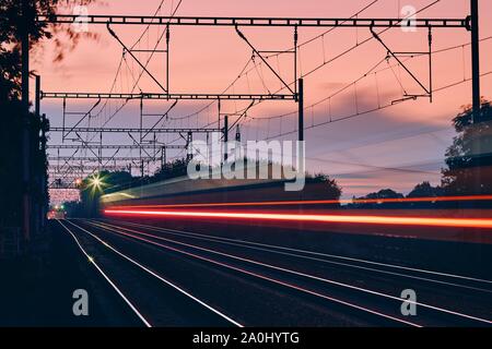 Gare à l'aube. Light trails de train de voyageurs sur la modernisation de la voie de chemin de fer. Banque D'Images