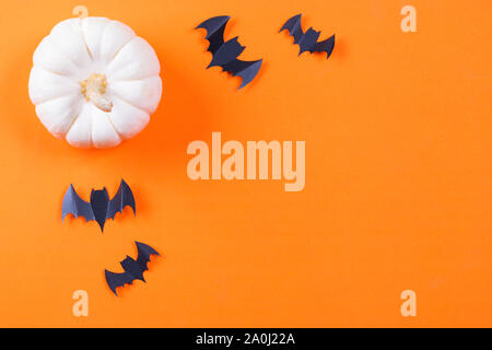 Halloween concept. Bande de papier noir et les chauves-souris citrouille fraîche sur fond de papier orange. Banque D'Images