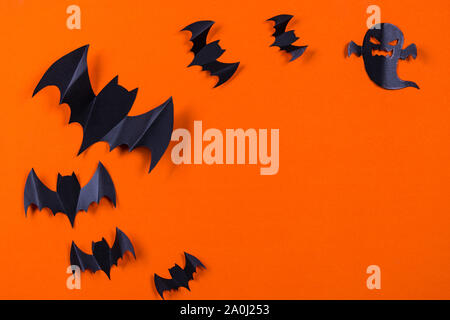 Halloween concept. Bande de papier noir et les chauves-souris ghost sur fond de papier orange. Banque D'Images