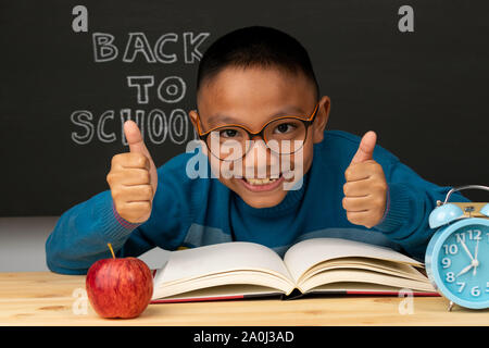 Élève de l'école primaire dans une collecte de lunettes avec la main. Enfant est prêt à apprendre. Retour à l'école. Apple, réveil, livres dans la salle de classe inte Banque D'Images