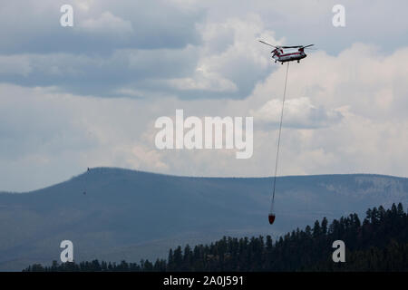 Un hélicoptère Chinook transporte l'eau de tomber sur un feu de forêt. Banque D'Images