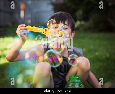 Un jeune garçon faisant des bulles à l'extérieur sur une journée d'été. Banque D'Images