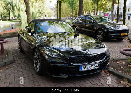 Vue avant des trois quarts d'une BMW 4 Roadster et d'une Porsche Cayenne, garée par la voie navigable Singelgracht, Amsterdam Banque D'Images