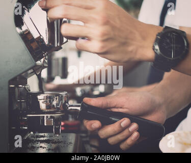 Close up hands de l'homme à l'aide de barista machine à café pour faire du café dans le café, Vintage la nuance de couleur. Banque D'Images