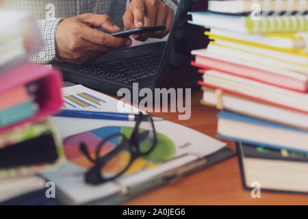 L'homme est à l'aide de téléphone mobile et le travail avec pile de documents sur Office 24, homme d'affaires est l'analyse marketing avec tableau de statistiques, d'affaires et O Banque D'Images