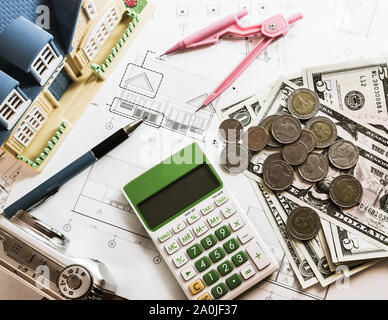 L'investissement pour la construction avec le budget, plan de construction, stylo, argent, maison modèle, boussole, appareil photo et une calculatrice sur table en bois Banque D'Images
