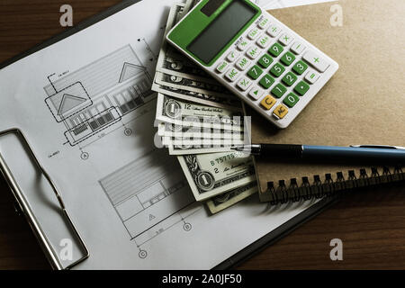 L'investissement pour la construction avec le budget, plan de construction, stylo, argent, ordinateur portable et calculatrice sur table en bois Banque D'Images