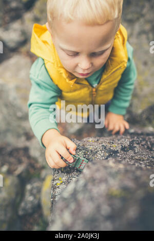 Bébé Garçon jouant avec des jouets sur un rocher. Petit enfant marche sur les montagnes rocheuses. Banque D'Images