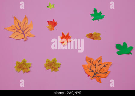 Faites de feuilles de papier sur un fond rose. Les feuilles d'automne papier rouge, orange, jaune la chute des feuilles. Banque D'Images