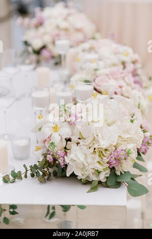 La décoration élégante du mariage moderne table avec bougies blanches et des fleurs dans des tons clairs. Banque D'Images