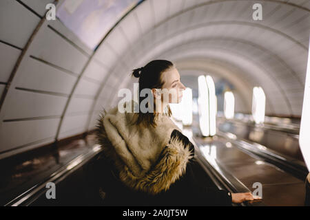 Young woman standing on escalator at subway station Banque D'Images