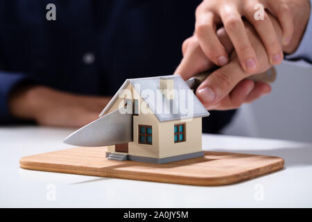 La coupe à la main du couple Modèle de maison miniature avec couteau sur planche à découper Banque D'Images