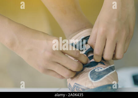 Fermer jusqu'à jeune homme s'asseoir à attacher les lacets cloutés avant de jouer au football. Banque D'Images