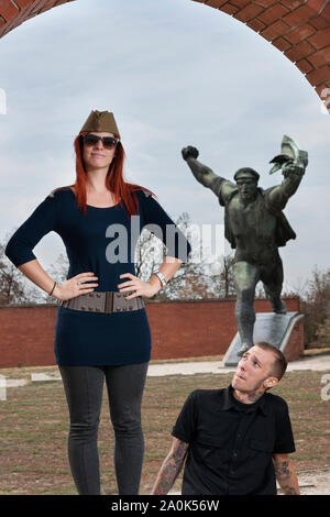 Red-haired woman portant un chapeau de soldat et un tatoué dans la vingtaine dictatorial socialiste visites de monuments commémoratifs et de chiffres au Memento Park Statue, Bud Banque D'Images