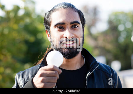 Jeune homme à la tresse et beard holding avec ampoule dans la main Banque D'Images