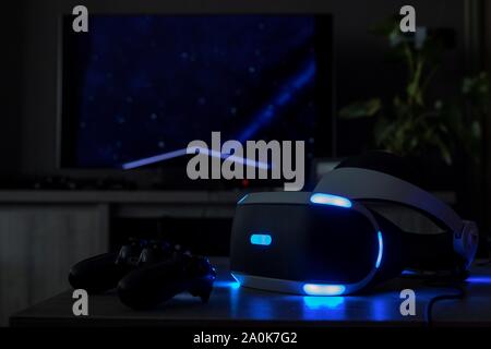 Brecht/Belgique - 12 juin 2019 : un casque de réalité virtuelle playstation dans une chambre noire sur une table en bois avec une tournée à la télévision dans le dos avec un c Banque D'Images