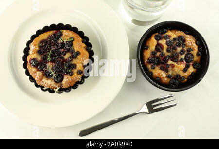 Chiacciata "all'uva' dans une assiette blanche, verre d'eau, de la fourchette. Sweet toscane typique focaccia avec de la pâte à pain, huile, sucre, raisin noir.fond blanc Banque D'Images