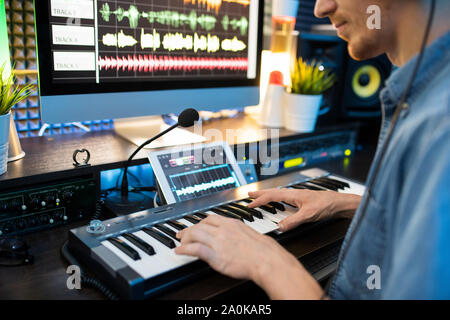 Jeune musicien assis par lieu de travail et d'appuyer sur des touches de clavier de piano Banque D'Images