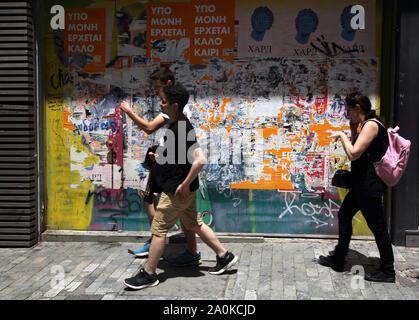 Monastiraki Athènes Grèce personnes marchant par barricadèrent bâtiment avec peeling vieux posters et Graffiti Banque D'Images