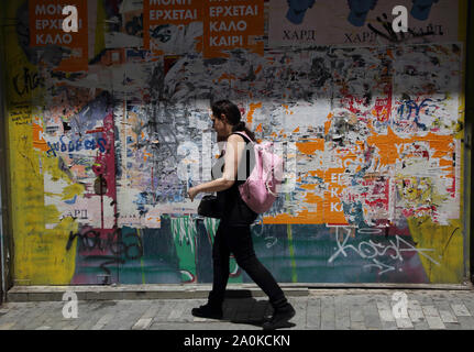 Monastiraki Athènes Grèce Femme avec sac à dos en randonnée avec de vieux bâtiment placardées des affiches et graffiti de déroulage Banque D'Images