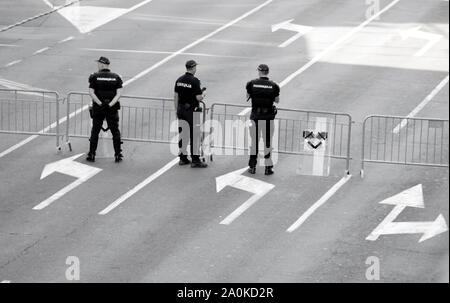 Belgrade, Serbie - Septembre 15, 2019 : trois policiers en face de barricade temporaire clôture sur rue, ville de l'arrière en noir et blanc Banque D'Images