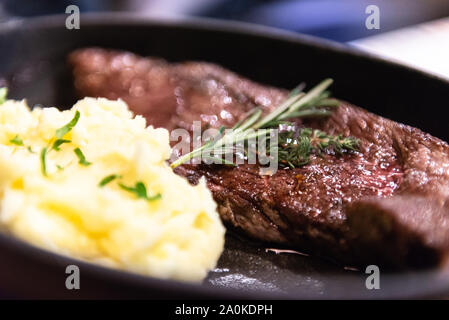 Pavé de boeuf avec des pommes de terre dans une casserole. Le romarin sur une viande. Banque D'Images