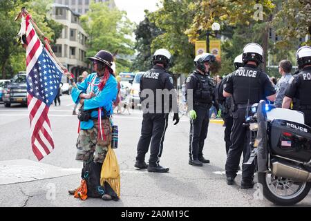 Un homme tenant un drapeau à l'envers à côté de la police à la grève du climat rassemblement à Eugene, Oregon, USA. Banque D'Images